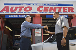 Deux personne devant un garage de réparation véhicule thermique